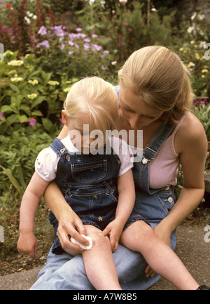 Mutter, die im Garten, Großbritannien, ein Kleinkind mit einer antiseptischen Wunde abschabt Stockfoto