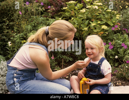 Mutter, die Sonnencreme auf das Gesicht eines Kindes im Garten anwendet, Großbritannien Stockfoto