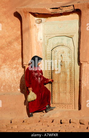 Frau im traditionellen Gewand gekleidet öffnet die alte Tür zu ihrem Haus aus Lehm Bou-Thrarar Marokko Stockfoto