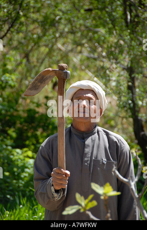 Lächelnde Bauer hält seine Hacke im Wald in der Nähe von Tourbist Marokko Stockfoto