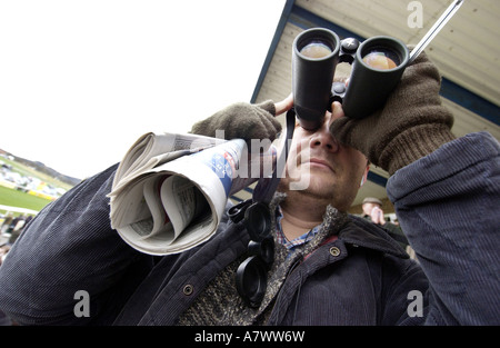 Ein Rennenbesucher mit einem Fernglas und einer gefalteten Zeitung Plumpton Racecourse, Sussex Stockfoto