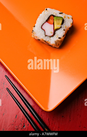 Sushi Rollen auf orange Teller mit Stäbchen Stockfoto