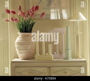 Stillleben mit rosa Tulpen in Keramikvase auf Brust mit klassischen Säule Ornamenten und weißen Lampe Stockfoto