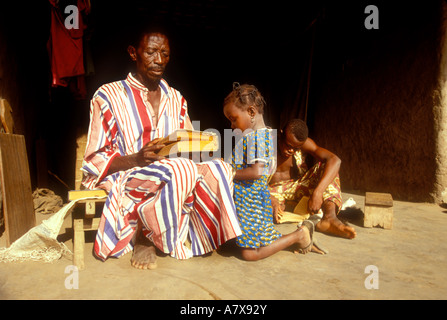 Ghana: Boku (Brong-Ahafo Region), älterer Mann (Muslim) mit Buch der Koran nach der Lektüre seiner Enkelin, März. Stockfoto