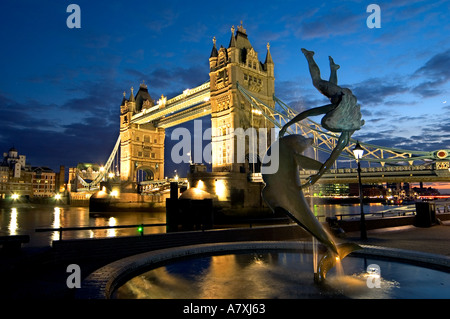 Statue der Meerjungfrau Delphin mit Tower Bridge im Hintergrund Nacht London England uk Stockfoto