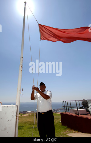 Chief Petty Officer Dudley Malgas wirft die rote Flagge vor der Bewaffnung der Mittag-Pistole in Kapstadt, Südafrika. Stockfoto
