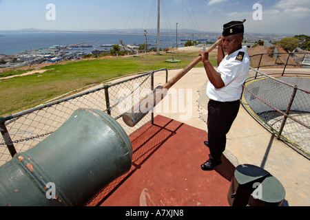 Chief Petty Officer Dudley Sennhütten mit einer hölzernen Druckstange drücken Sie die Ladung in die Mündung der Pistole Mittag Kanone in Kapstadt. Stockfoto