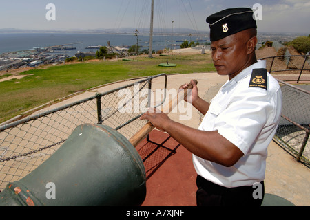 Chief Petty Officer Dudley Sennhütten mit einer hölzernen Druckstange drücken Sie die Ladung in die Mündung der Pistole Mittag Kanone in Kapstadt. Stockfoto