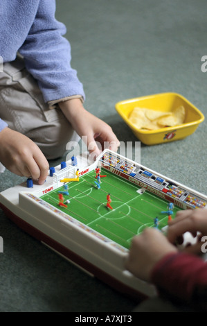 Zwei Jungen spielen kleine Tabelle Fußballspiel mit einer Schüssel Chips Stockfoto