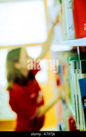 junge Frau in Bibliothek Bücher wieder sehr bunten Bücher setzen möglicherweise Kunstbücher, die Sie Lächeln Spaß an ihrer Arbeit Stockfoto