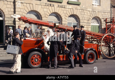 Glastonbury Hochzeitsgäste auf und um restaurierte altmodische Feuerwehrmaschine vor dem Rathaus geparkt Fotograf Besuch Somerset England Großbritannien Stockfoto