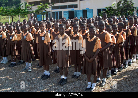 Gemischte Gruppe von jungen Mädchen Schulkinder aufgereiht für die Montage außerhalb Schulgebäude - vor Klassen in Ghana, Westafrika Stockfoto