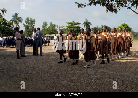 Gruppe von Mädchen der Mittelschule in Uniformen verlassen Schulversammlung im Freien gehalten, für Klassenzimmer und vor dem Unterricht in Ghana Westafrika Stockfoto