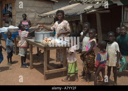 Dorf-Frau mit Essen Snacks für Kinder vom Marktstand in Ghana Westafrika Stockfoto