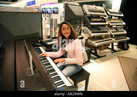 Mädchen spielen Klavier; Ein attraktives junges Mädchen versucht, eine Tastatur in ein Piano store, Cambridge UK Stockfoto