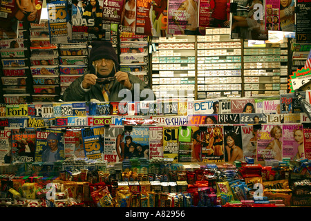 Ein Mann verkauft Zeitungen und Zeitschriften auf einer Straßenseite Shop in New York USA Stockfoto