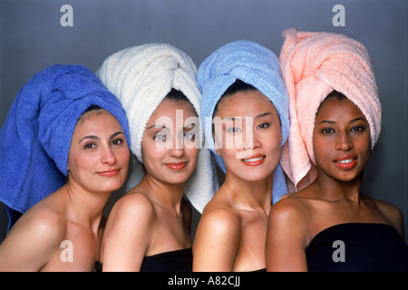 Vier Frauen aus ethnischen Mischung mit Haaren eingewickelt in bunte Handtücher gerichtete Kamera Stockfoto
