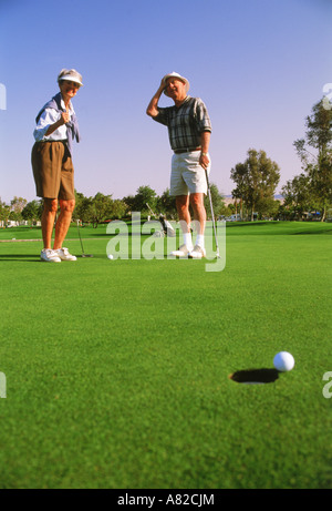 Paar in ihren 70ern beobachten Putt auf grün beim Golfen in Palm Springs Kalifornien Stockfoto