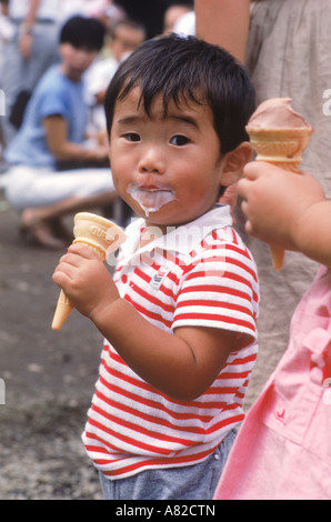 Japanische junge Essen und Eis von einem Kegel tragen Stockfoto
