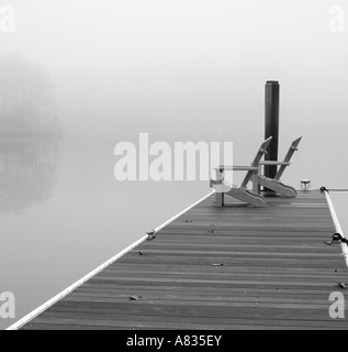 Adirondak Stühle auf dock mit nebligen See im Hintergrund Stockfoto