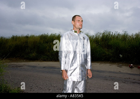 Junger Mann in glänzenden silbernen Kleid Stand mit hohen Wiese hinter Stockfoto