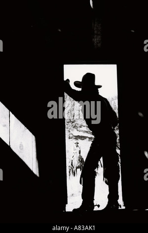 Ein Cowboy in der Tür einer Scheune in Oregon mit einer anderen Cowboy Reiten im Hintergrund stehe Stockfoto
