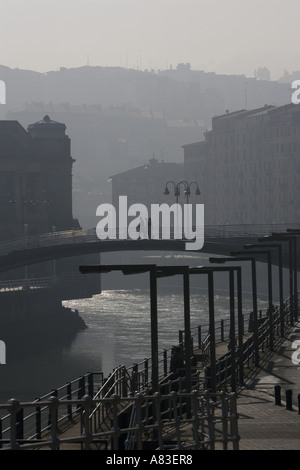 Menschen zu Fuß über Brücken über den Fluss Nervion Bilbao Hintergrundbeleuchtung durch das Sonnenlicht am frühen Morgen. Stockfoto