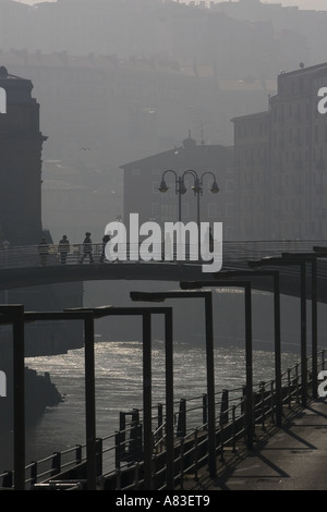 Menschen zu Fuß über Brücken über den Fluss Nervion Bilbao Hintergrundbeleuchtung durch das Sonnenlicht am frühen Morgen. Stockfoto