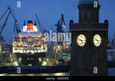 Die Queen Mary II im Trockendock von Blohm + Voss und historische Uhr Turm von St. Pauli Landungsbruecken in Hamburg, Deutschland Stockfoto