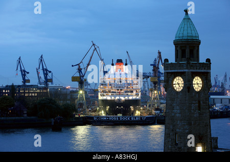 Historische Uhr Turm der Landungsbrücken Gebäude und Queen Mary II im Trockendock von Blohm + Voss in Hamburg, Deutschland Stockfoto