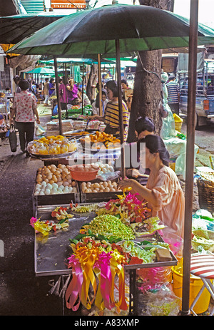 Thai Früchte, Gemüse und Blumengirlanden auf bürgersteig Stände, gebratenes Huhn nach hinten sichtbar Stall, Pak Khlong Talad Markt, Bangkok, Thailand Stockfoto