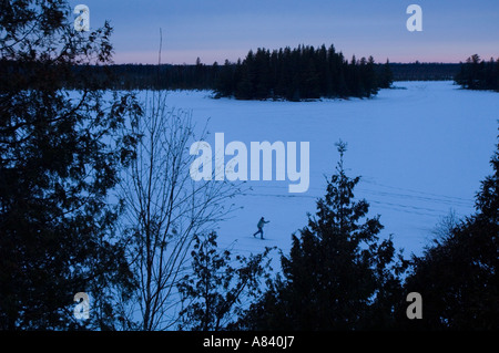 Ein Langläufer führt einen Abend Ski über Sand Lake Schneeschuh Land Lodge Isabella Minnesota Stockfoto