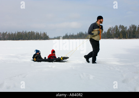 Ein Mann zieht zwei kleine Kinder auf einem Schlitten über einen See Schneeschuh Land Lodge Isabella Minnesota Stockfoto