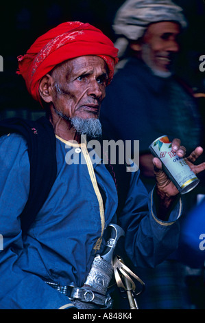 Oman. Stadt von Taqah im Süden. Alter Soldat Ali Dablan al-Mashadi immer ein kühles Getränk. Hinweis traditionelle omanische Khanjar Dolch Stockfoto