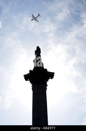 Ein Flugzeug fliegt vorbei an Nelsons Statue an der Spitze der Spalte Nelsons in Trafalgar Square, London, England, UK Stockfoto