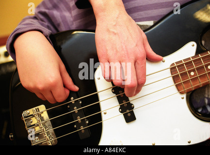 Lehrer zeigt einen jungen Spielanleitung Basis während einer Unterrichtsstunde in der Musik in der Schule Stockfoto