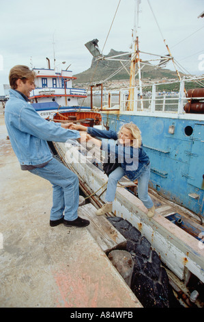 Junges Paar tragen Jeans Klettern heraus aus alten Boot in einem Hafen. Stockfoto