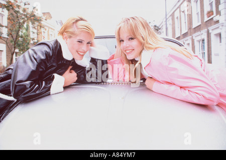 Zwei junge Frauen im Freien in London Straße, stützte sich auf VW-Käfer-Auto. Stockfoto