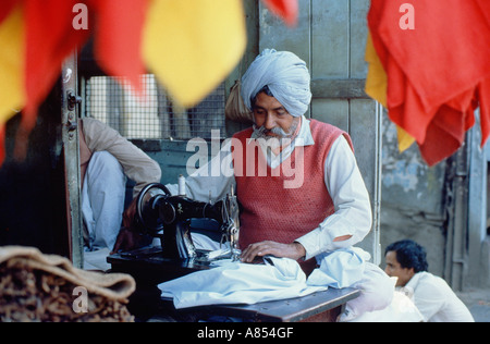 Indien. Delhi. Lokale Industrie. Sikh Mann Schneider arbeiten Nähmaschine. Stockfoto