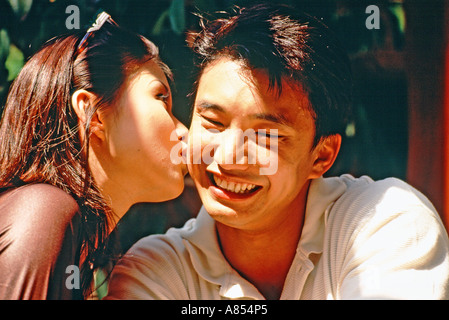 Junges Paar im Freien. Frau Mann auf die Wange küssen. Stockfoto