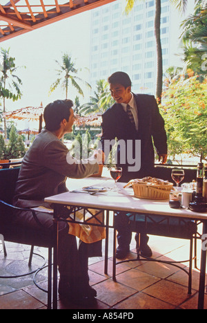 Zwei Männer gruss Handshake auf der Terrasse von Singapur Restaurant. Stockfoto
