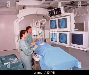 Arzt und Krankenschwester mit Patienten im Krankenhaus Angiographie Scan Zimmer. Stockfoto
