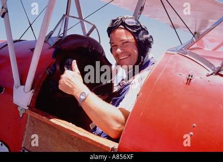 Junger Mann Flieger Pilot geben Daumen nach oben Zeichen vom Cockpit des altmodischen Doppeldecker. Stockfoto