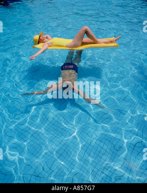 Zwei Personen im Pool. Mann Schwimmen unterhalb liegende Frau auf Luft Bett. Stockfoto