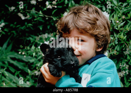 Outdoor Portrait junge hält ein Haustier schwarze Hündchen. Stockfoto