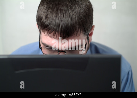 Geschäftsmann, die Arbeit an seinem tragbaren Laptop mit Kopf und Gesicht teilweise verdeckt durch den Bildschirm Stockfoto