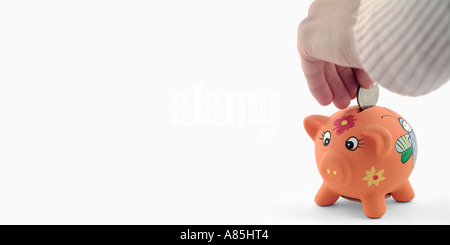 Frauen-Hand, eine Münze in ein Sparschwein Stockfoto