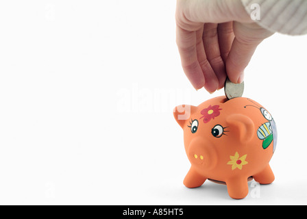 Frauen-Hand, eine Münze in ein Sparschwein Stockfoto