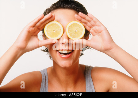 FRAU SPIELT MIT ZITRONE SCHEIBEN GLÄSER AUF WEIßEM HINTERGRUND Stockfoto