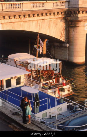 Paar am Seineufer in Paris bei Sonnenuntergang mit Boote vor Anker in der Nähe von Pont De La Concorde Stockfoto